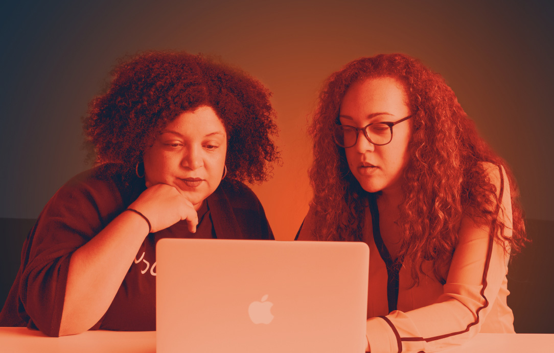 Two women of color (female entrepreneurs) looking at laptop.